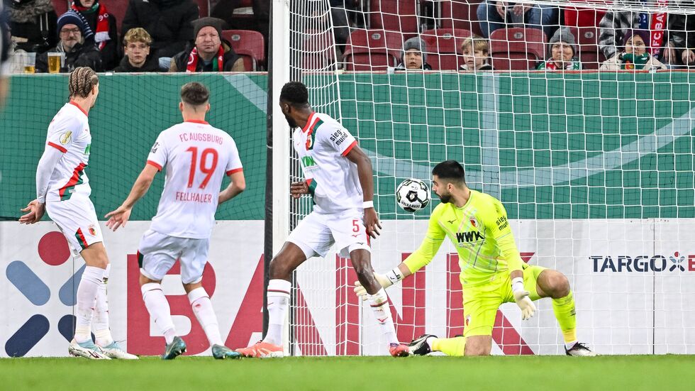 Der Schuss, der zum Augsburger Pokal-K.o. führt. Verteidiger Chrislain Matsima (M) fälscht den Ball auch noch unglücklich und damit unhaltbar ab.  Der Schuss, der zum Augsburger Pokal-K.o. führt. Verteidiger Chrislain Matsima (M) fälscht den Ball auch noch unglücklich und damit unhaltbar ab.