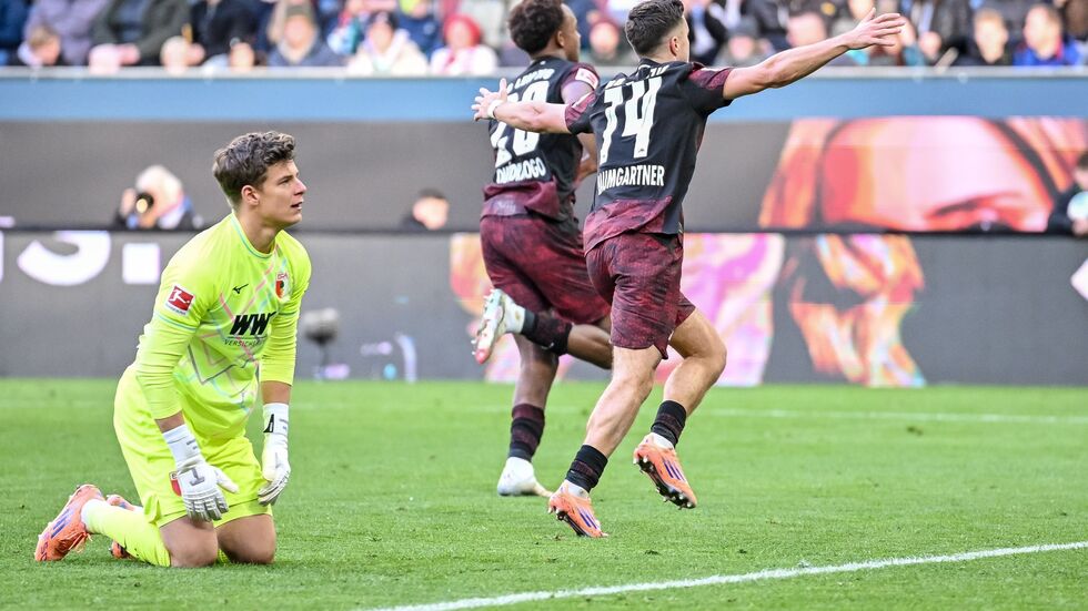 Augsburgs Torwart Finn Dahmen kauert bedröppelt am Boden, die Leipziger Assan Quedraogo (M) und Christoph Baumgartner (r) bejubeln das 0:5.  Augsburgs Torwart Finn Dahmen kauert bedröppelt am Boden, die Leipziger Assan Quedraogo (M) und Christoph Baumgartner (r) bejubeln das 0:5.