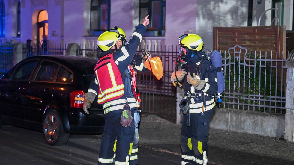 Der Einsatzleiter zeigt seinen Kollegen etwas bei dem brennenden Haus.