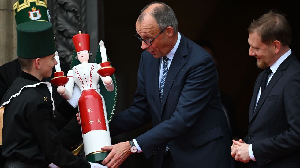 Bundeskanzler Friedrich Merz (CDU) erhält neben Ministerpräsident Michael Kretschmer (CDU, r) bei seiner Ankunft vor der Staatskanzlei eine erzgebirgische Engelsfigur. 