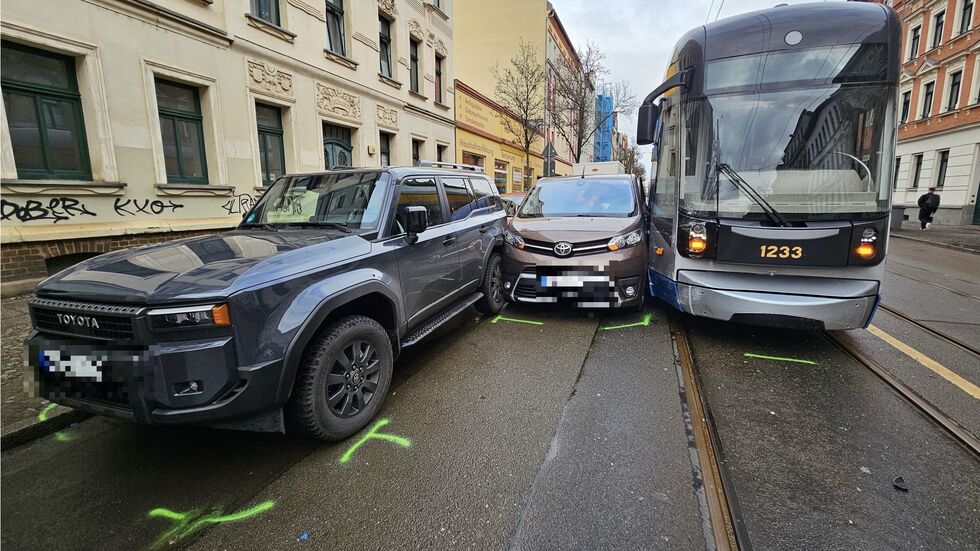 Der Toyota steckt zwischen einer Straßenbahn und zwei Autos am Straßenrand fest.