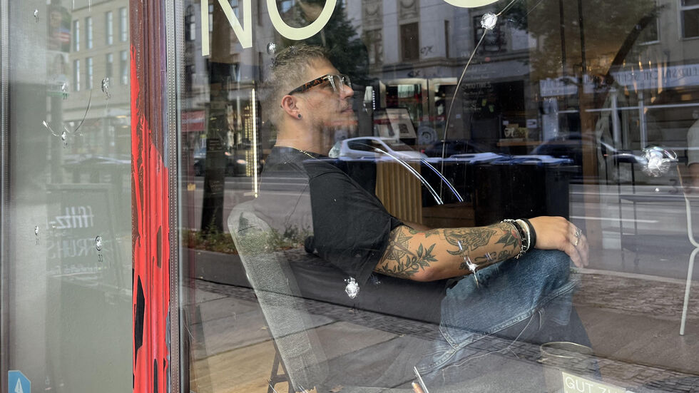 Renè Wagner sitzt hinter den zerstörten Fensterscheiben seines Cafés "Stay".