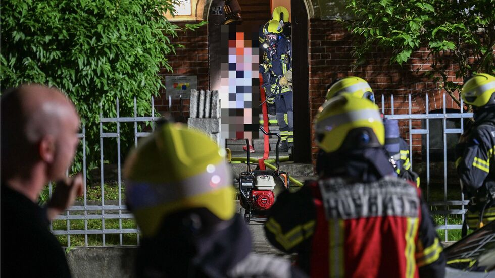 Hier wird die verletzte Frau mit einer übergestülpten Atemschutzmaske aus dem brennenden Haus gebracht.