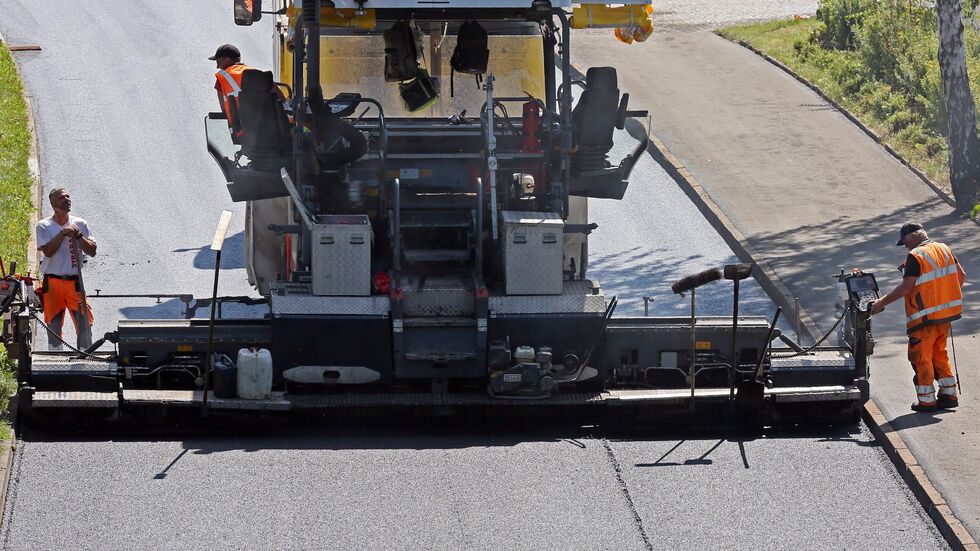 Bauarbeiter beim Asphaltieren einer Straße (Symbolbild). Bauarbeiter beim Asphaltieren einer Straße (Symbolbild).