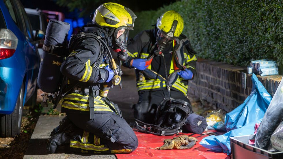 Feuerwehrleute während des Einsatzes neben dem Brandhaus.