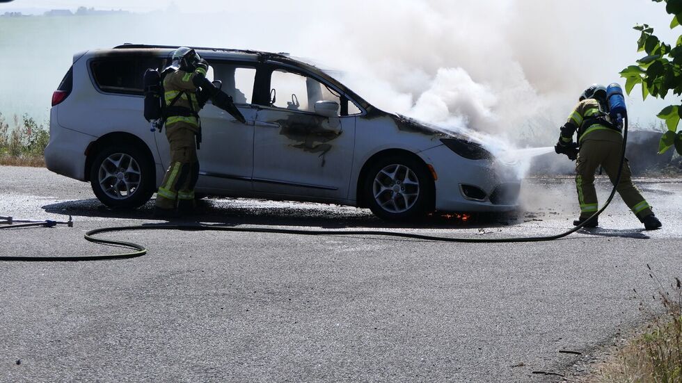 Feuerwehrleute beim Löschen des qualmenden Wagens. 